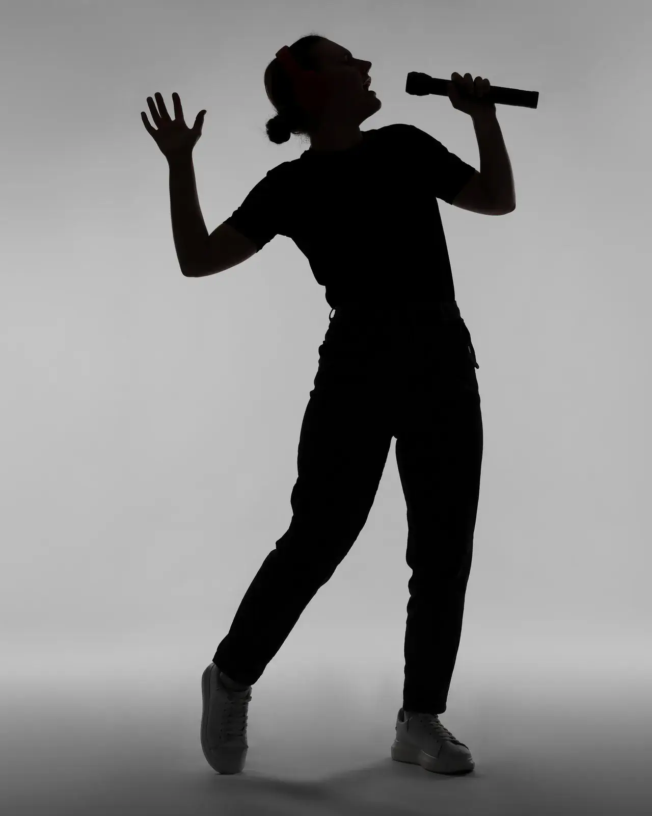Silhouette of a vocalist conducting with arm raised — Concerto Music Place choir director for schools