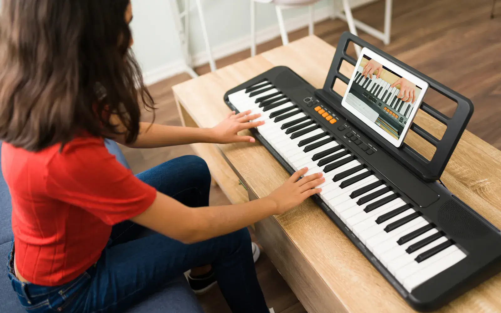 A child practising keyboard at home with an online music lesson on a tablet — live online music classes at Concerto Music Place